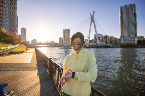istock Japanese woman using smart watch during jogging at riverside 1353800967