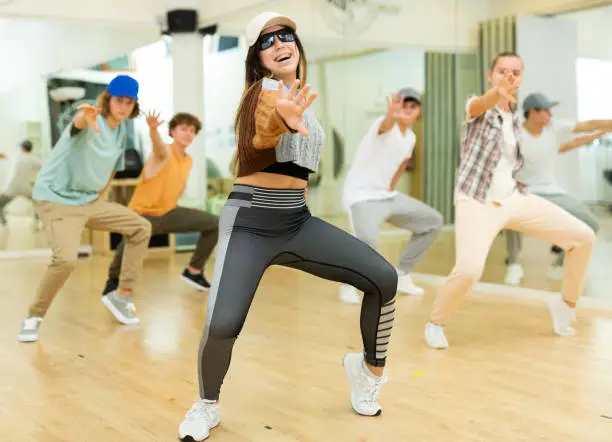 Photo of Cheerful hispanic teenage girl practicing hip-hop movements in studio