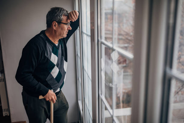 istock A depressed man looks out of a glass window 1353808272