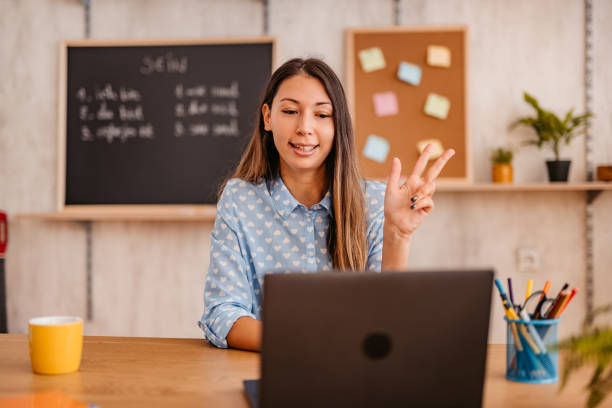 Female teacher giving foreign language lesson online Happy teacher woman giving foreign language lesson in live, broadcasting class during the Coronavirus, using laptop. online tutors stock pictures, royalty-free photos & images
