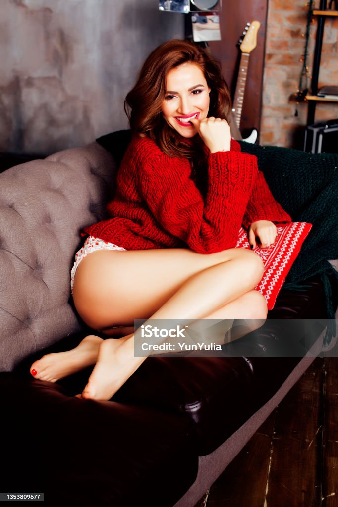young pretty stylish woman in red winter sweater at couch in home interior happy smiling, lifestyle people concept young pretty stylish woman in red winter sweater at couch in home interior happy smiling, lifestyle people concept close up Sensuality Stock Photo