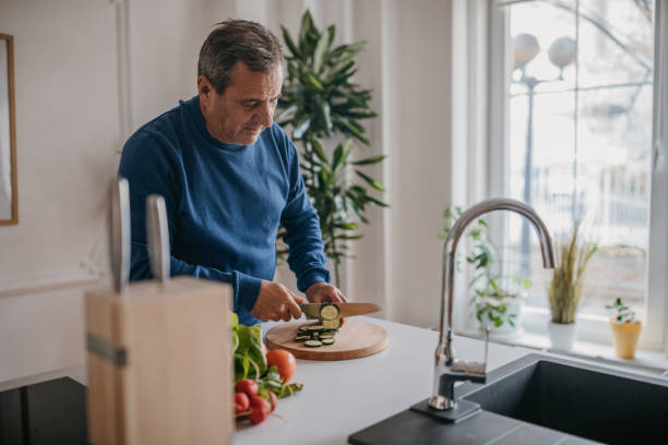 istock The man prepares lunch himself, cuts vegetables 1353811472