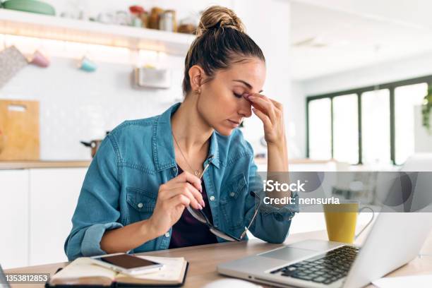 Stressed Business Woman Working From Home On Laptop Looking Worried Tired And Overwhelmed Int He Kitchen At Home Stock Photo - Download Image Now