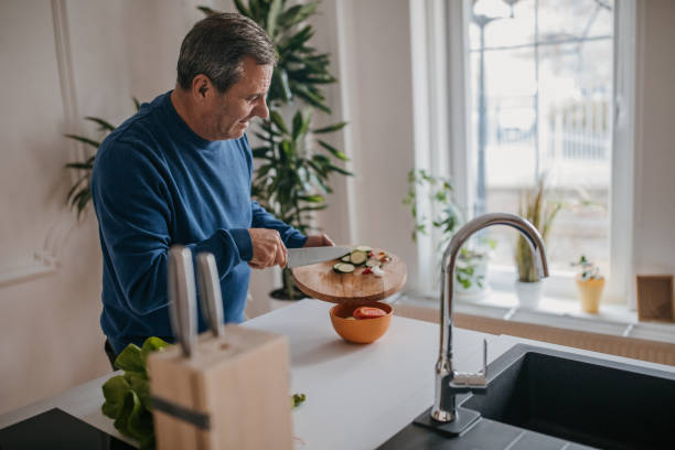 istock The man prepares lunch himself, cuts vegetables 1353812947