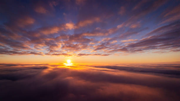 istock Drone photo of setting sun above clouds in the sky 1353814204