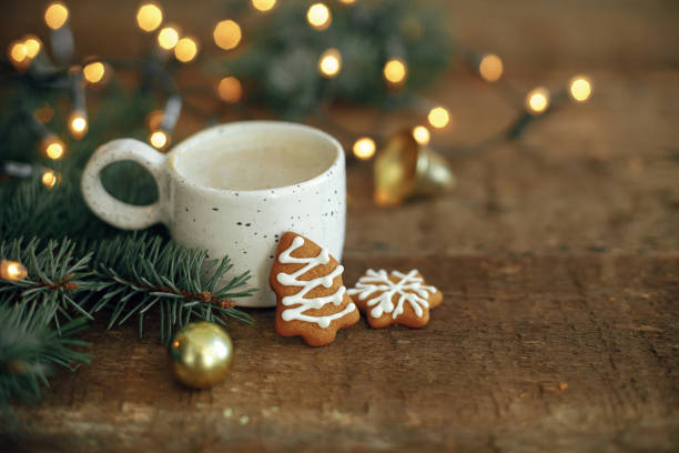 istock Winter time. Christmas gingerbread cookies, coffee, fir branches on rustic table with lights. Hygge 1353814483