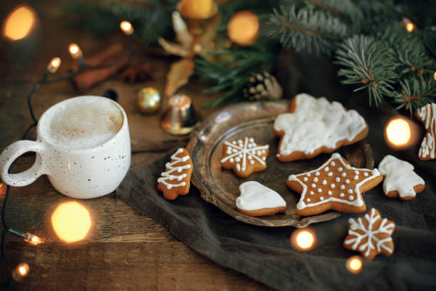 istock Christmas gingerbread cookies, coffee, fir branches, lights on rustic  table. Happy Holidays! 1353815094