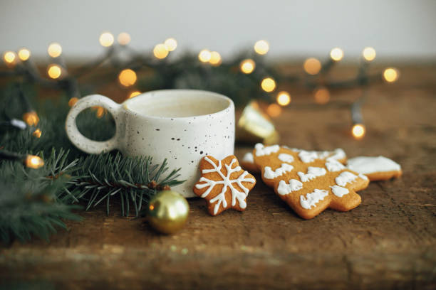 istock Christmas gingerbread cookies, coffee, fir branches on rustic table with lights. Winter rustic hygge 1353816266