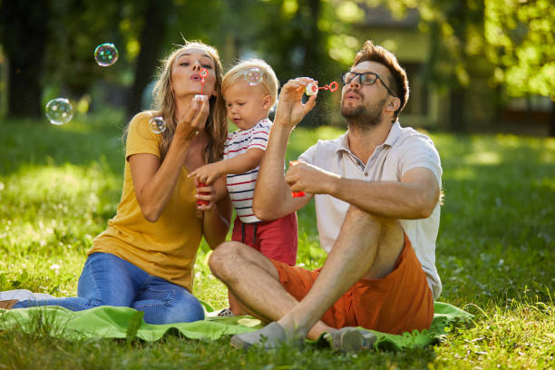 istock Family having fun blowing soap bubbles in park 1353817348
