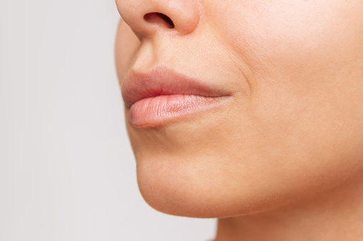 Cropped shot of a young caucasian pretty woman with soft smooth skin and natural full lips on a white background. Close-up