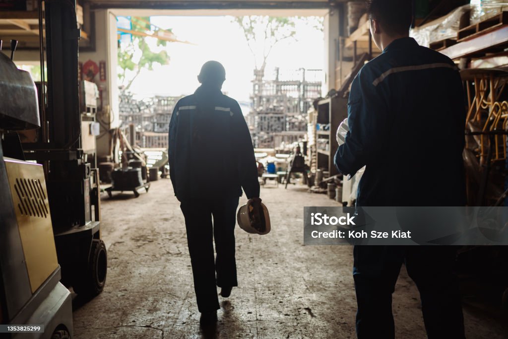 Mental health and wellbeing - A pair of Asian factory coworkers stepping out for a rest Construction Industry Stock Photo