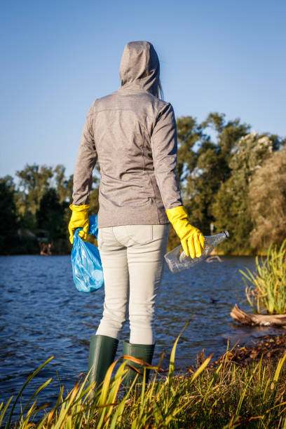 istock Environmental volunteer with protective glove holding garbage bag and plastic bottle 1353826549