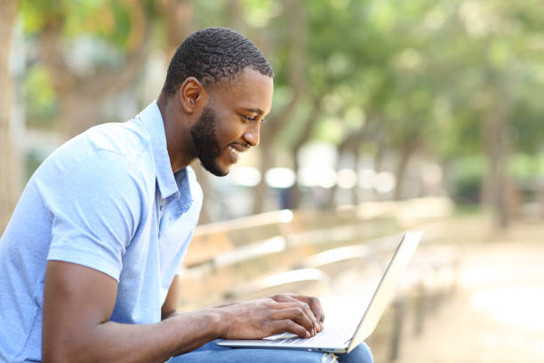 istock Man with black skin using laptop in a park 1353826869