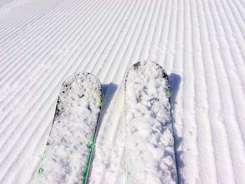 Close-up showing skis on a freshly groomed piste at a ski resort.