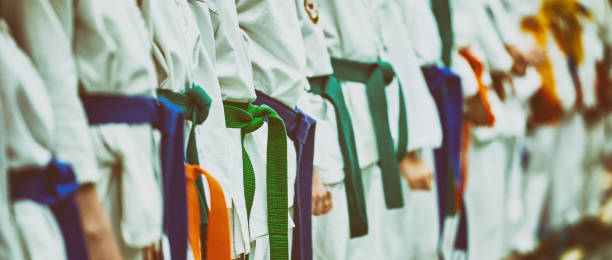 concetto di karate, arti marziali. costruzione di studenti nella sala prima della formazione. kimono, diverse cinture, diversi livelli di allenamento - tae kwon do foto e immagini stock