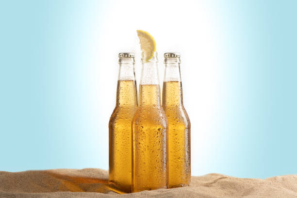istock Bottles of Beer on the beach isolated on white blue background. 1353837611