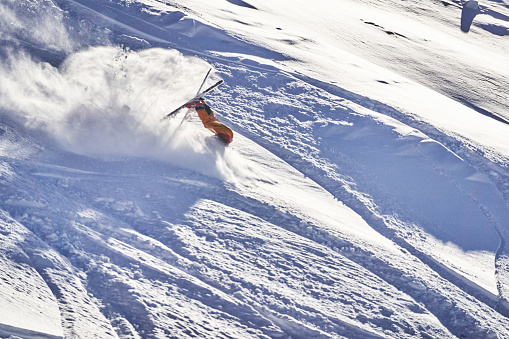 Skier falls down at speed, on snowy mountain ridge