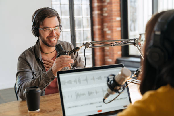 istock Two podcasters in headphones laughin while recording audio podcast 1353838663