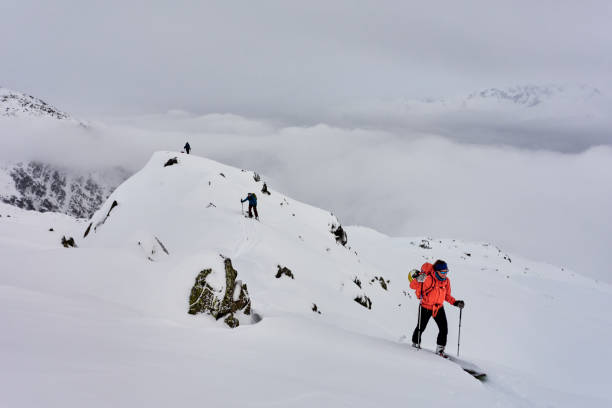istock Friends backcountry ski down snowy mountain ridge 1353840460