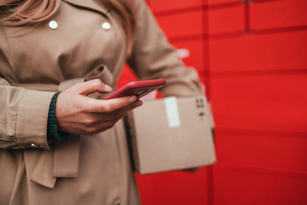 istock Woman using automated self service post terminal machine or locker to deposit the parcel for storage. Delivery, online ordering, food delivery 1353841324