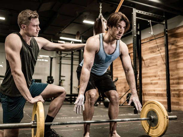 istock Young Man lifting weights with his trainer in the Gym 1353841816