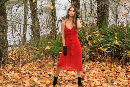 A woman outdoors in Autumn in a red sleeveless dress.