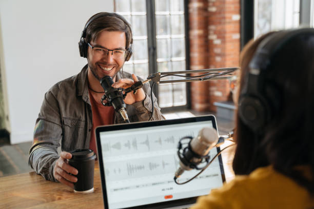 istock Smiling podcaster looking at camera while making audio podcast with his colleague 1353843058