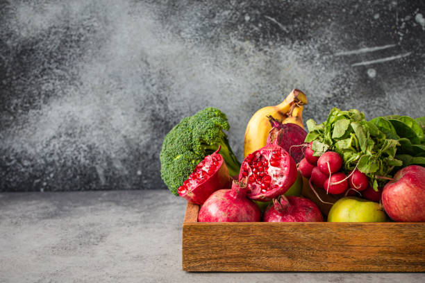 istock Fresh fruit and vegetables in wooden tray copy space 1353843151