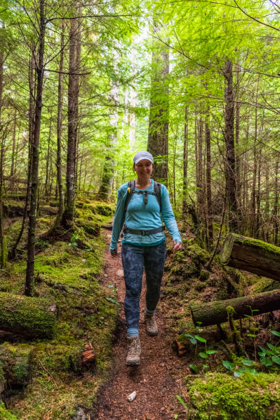 istock Woman hikes up through lush, autumnal forest 1353847422