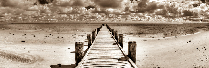 A jetty on the Wadden Sea on the German North Sea coast at low tide in black and white