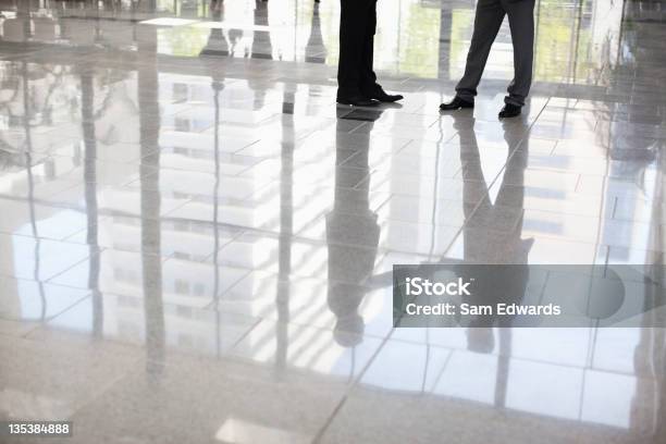 Foto de Empresários Em Pé Juntos No Lobby e mais fotos de stock de Chão - Chão, Escritório, Reflexo - Efeito de luz