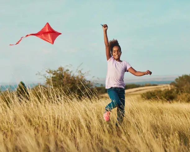 Happy little girl running playing with kite outdoors