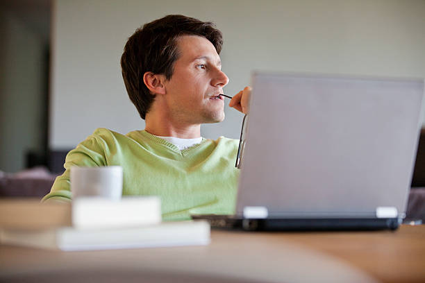 uomo seduto con il computer portatile e di pensiero - distracted foto e immagini stock