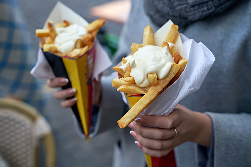 Belgian frites with mayonnaise in Brussels, Belgium. Tourist holds two portions of fries in hands in the street.