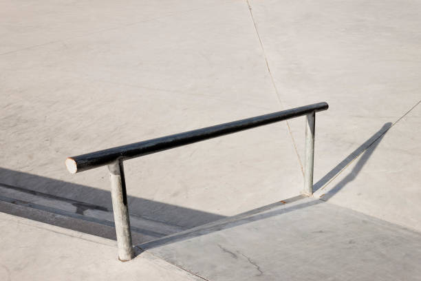 istock Sloped metal rail for grind tricks in an empty concrete skatepark 1353849700