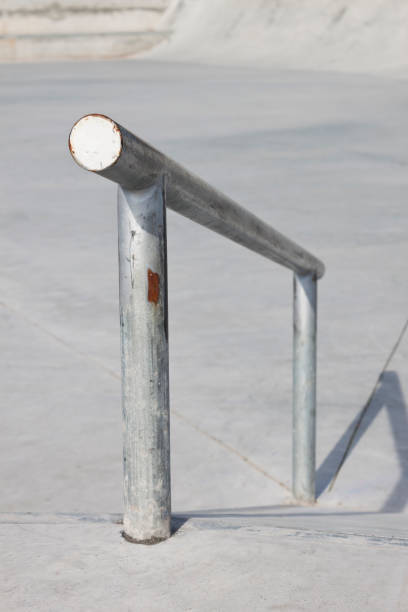 istock Sloped metal rail for grind tricks in an empty concrete skatepark 1353849761