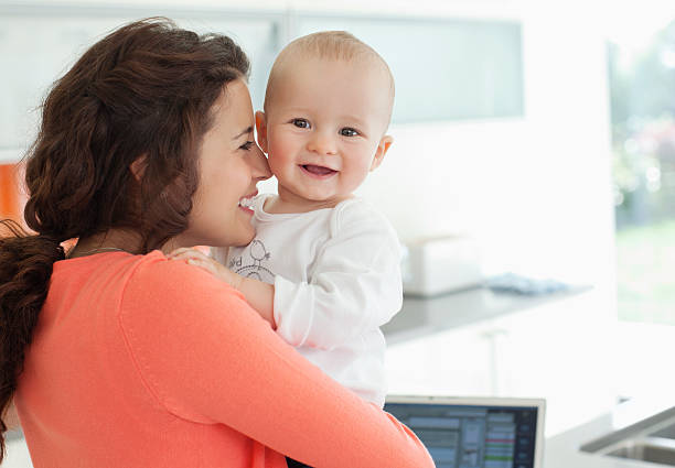 sonriente bebé madre sostiene - women mother baby happiness fotografías e imágenes de stock