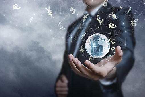 Businessman supports the international currency market in his hand against the background of the sky.