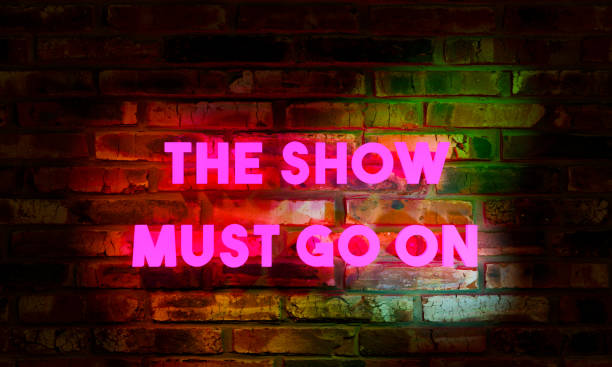 istock The show must go on. Illuminated letters against an old weathered red brick wall. 1353850761