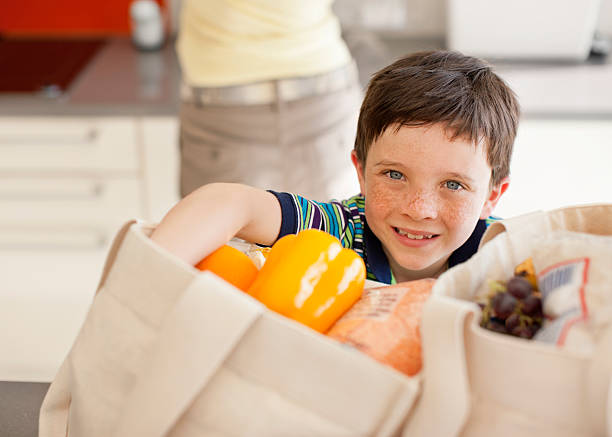 Boy unloading groceries from reusable bag  Hove stock pictures, royalty-free photos & images