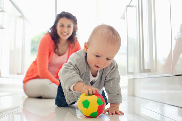 mère en regardant bébé jouant avec le ballon - rampe photos et images de collection