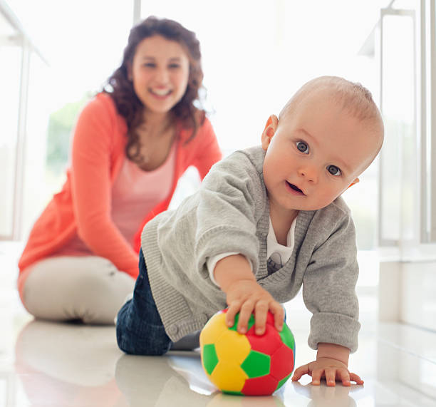 Mother watching baby playing with ball  Hove stock pictures, royalty-free photos & images