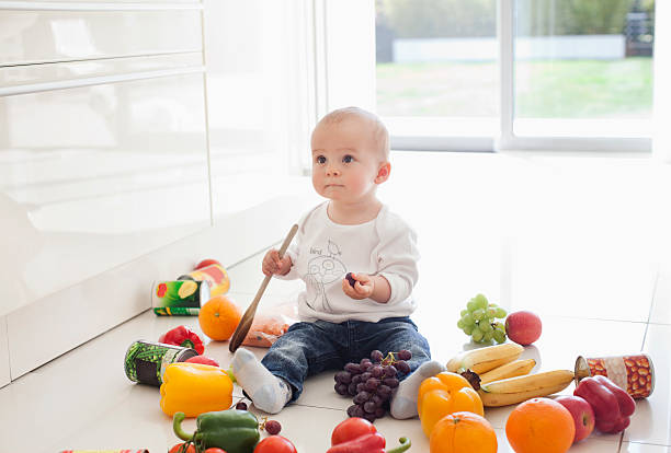 bebé que juega en el suelo con alimentos - baby food fotografías e imágenes de stock