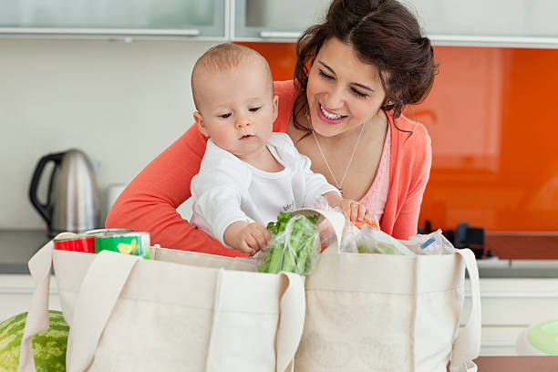 Mother holding baby and unloading groceries  unloading photos stock pictures, royalty-free photos & images