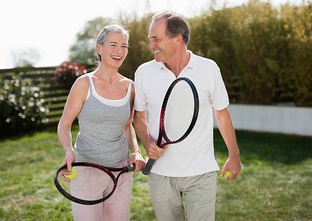 pareja sosteniendo raquetas de tenis al aire libre - tennis couple women men fotografías e imágenes de stock