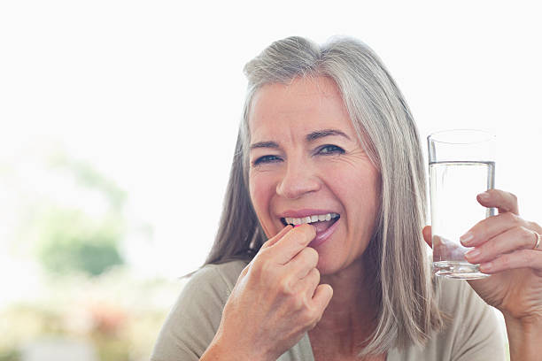 femme tenant le verre d'eau en prenant la pilule - water women glass healthy eating photos et images de collection