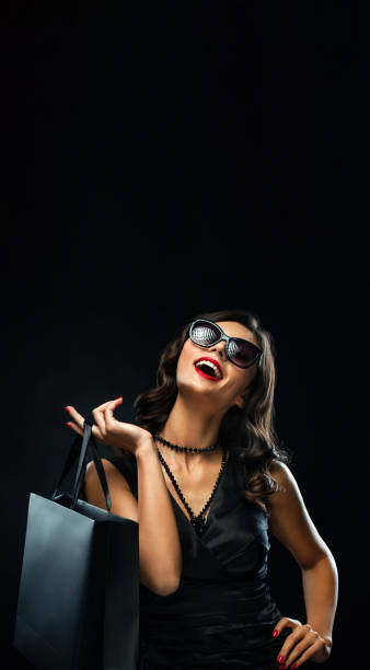 Black friday sale concept. Shopping woman holding grey bag isolated on dark background in holiday stock photo