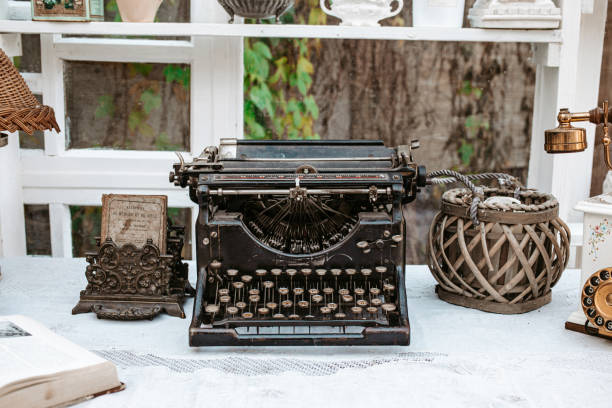 Vintage old typewriter in shabby chic interior Vintage old fashioned typewriter machine on wooden desk next to window in light white shabby chic vintage french Provence country cottage interior room with antique objects mclean county stock pictures, royalty-free photos & images