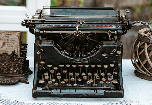 Close-up of Vintage old fashioned typewriter machine Underwood on desk next to window in light white shabby chic vintage country cottage interior room