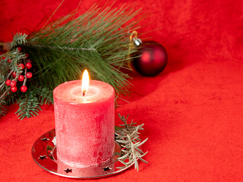 Red Christmas candle and Christmas decorations on a red background. High quality photo